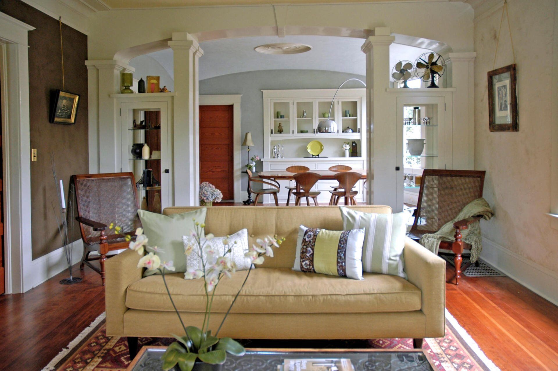 View of the living room sofa with the dining room visible under the archway partition between rooms.