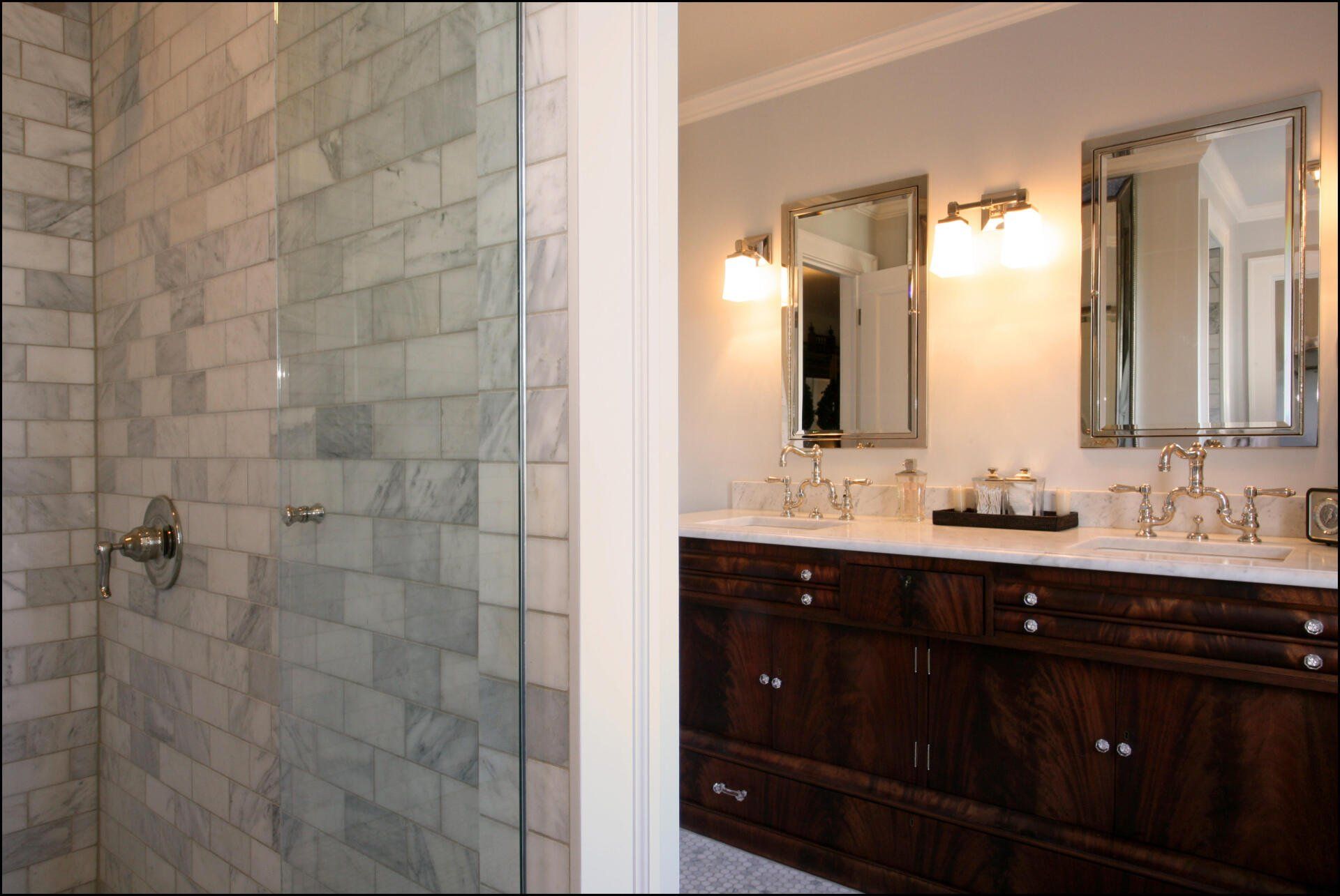 Peeking around the corner from the marble tiled shower to the antique vanity cabinet.