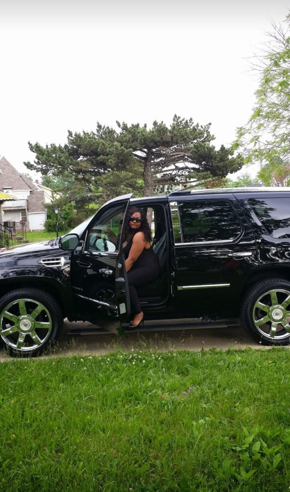 A woman is sitting in the back seat of a black suv.