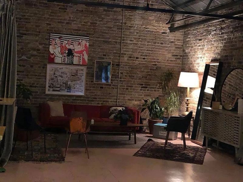 A living room with a red couch , chairs , a table and a mirror.