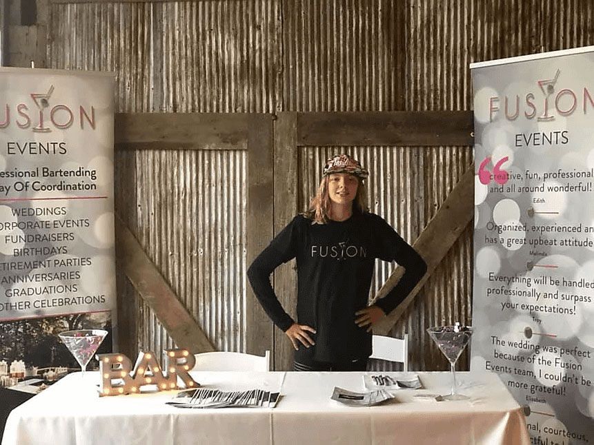 A woman is standing in front of a table with a sign that says fusion events.