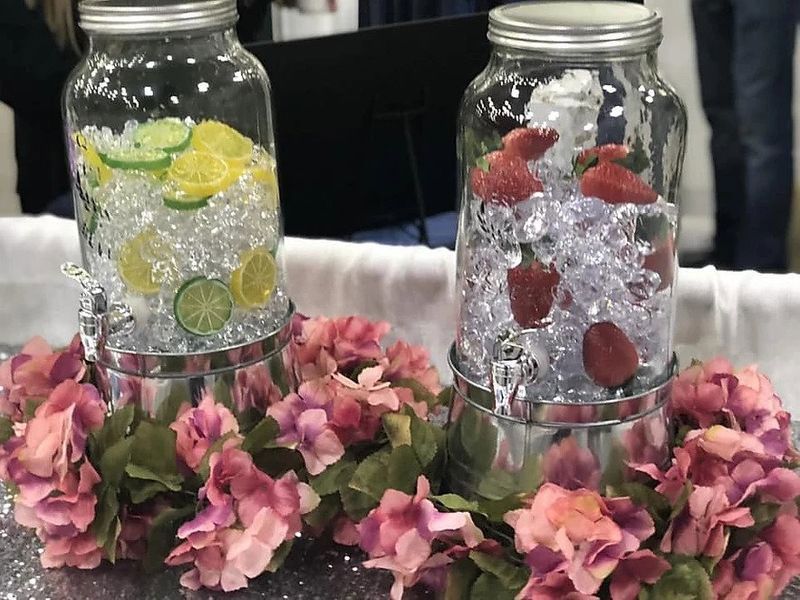Two mason jars filled with ice and fruit are sitting on a table.