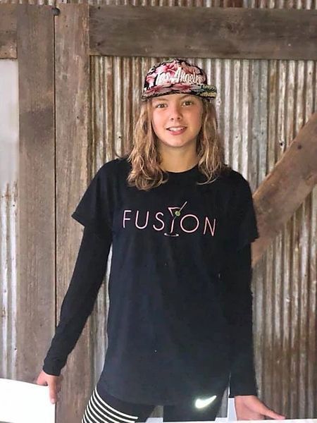 A young girl wearing a black t-shirt with the word fusion on it