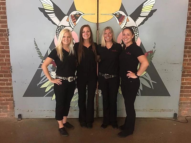 A group of women standing in front of a mural