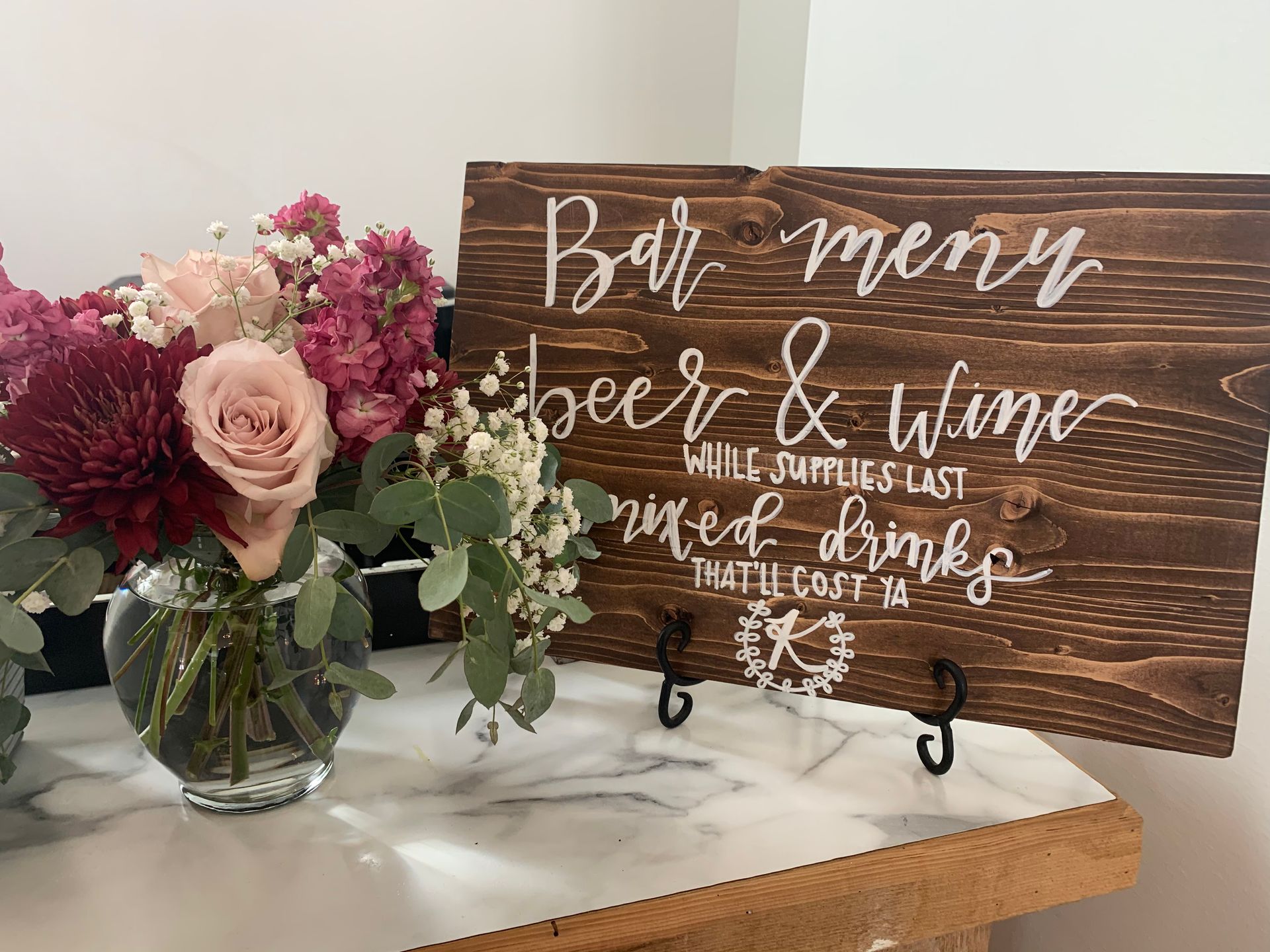 A large wooden bar in a barn with a chandelier hanging from the ceiling.