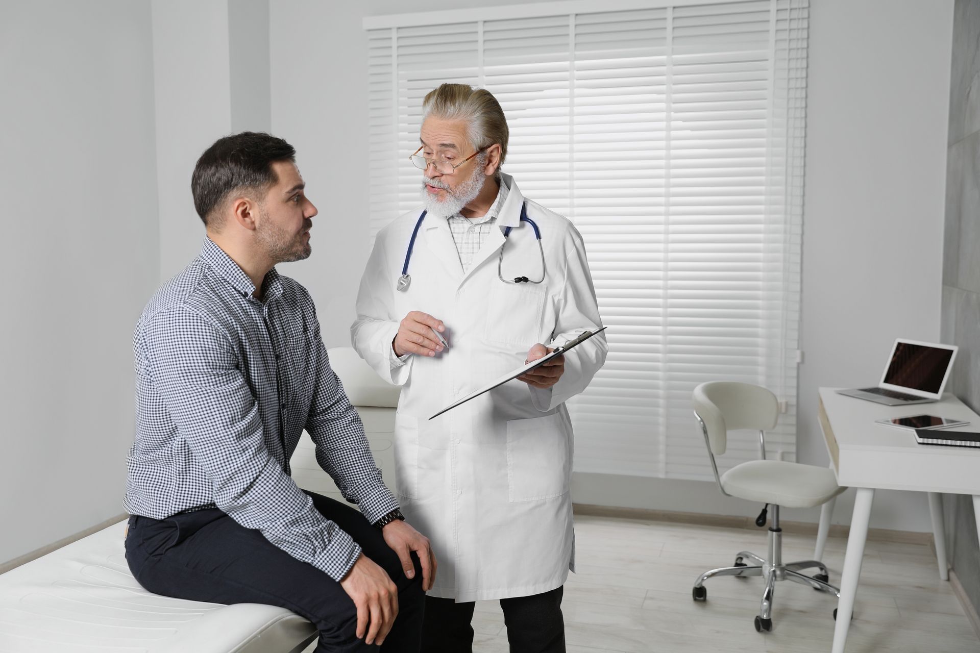 A doctor is talking to a patient who is sitting on a bed.