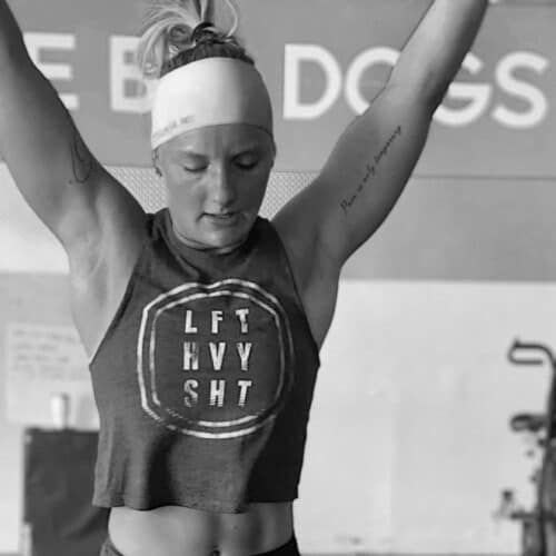 Woman in athletic wear raises arms, working out.