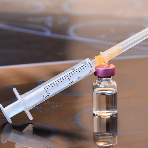 A syringe is sitting next to a bottle of liquid on a table.