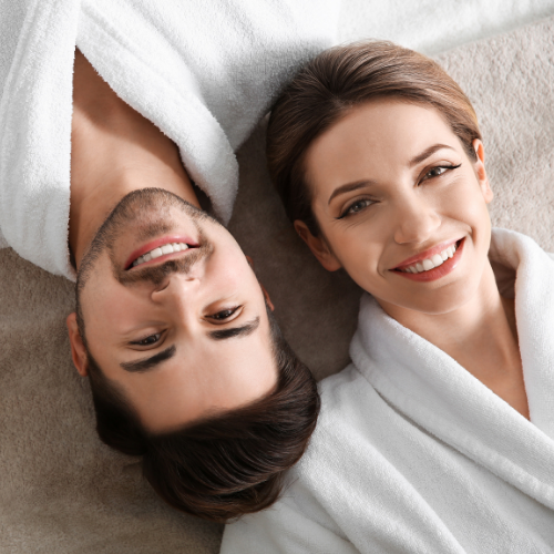 A man and a woman are laying next to each other on a bed and smiling.