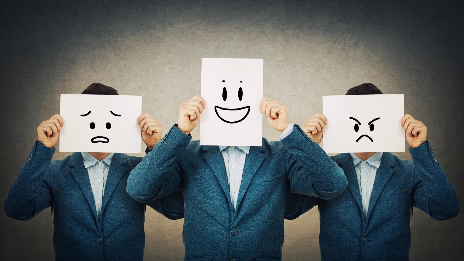Three men in suits are holding signs with smiley faces on them in front of their faces.