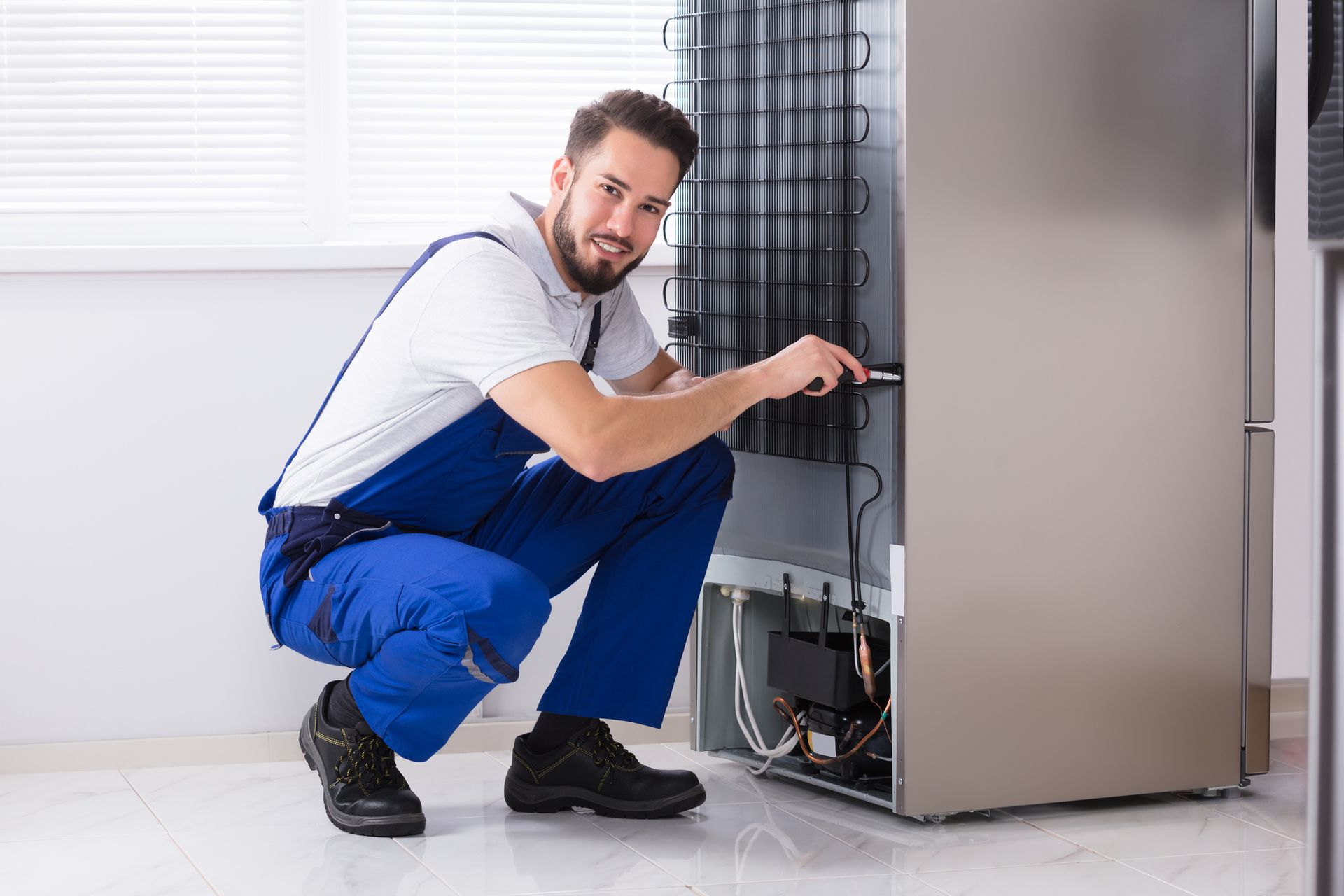 A man is working on a refrigerator in a kitchen.