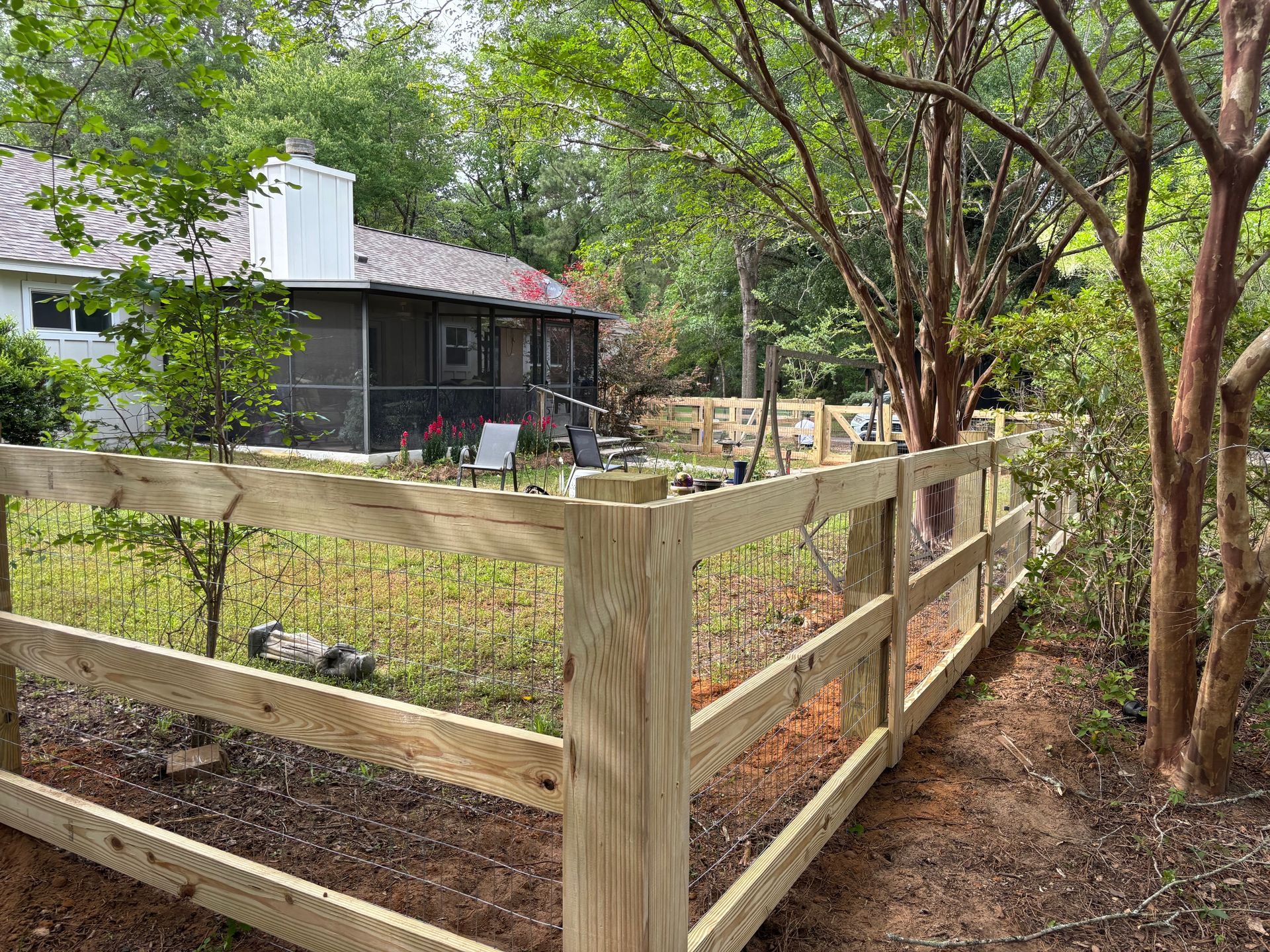 A wooden fence surrounds a yard in front of a house.