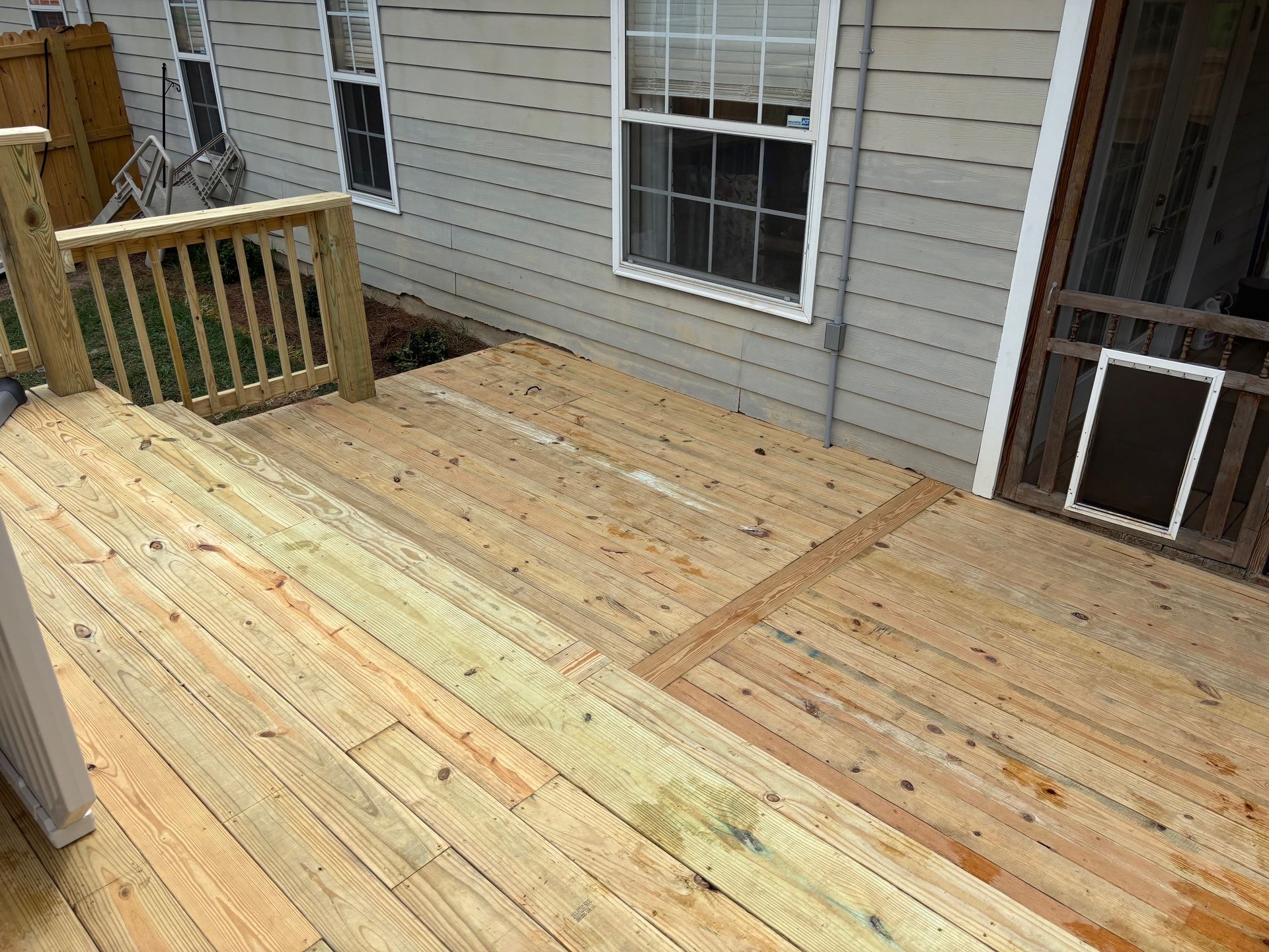A wooden deck is sitting in front of a house with a screened in porch.