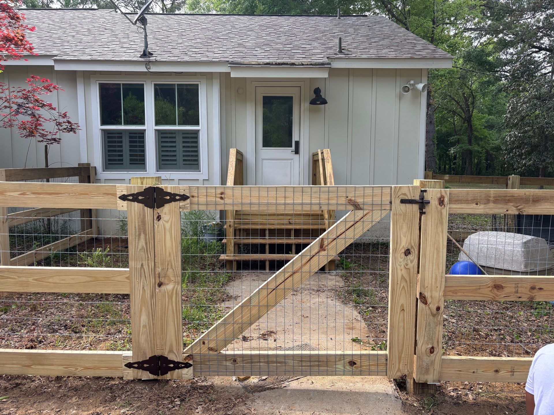 A wooden fence is in front of a white house.