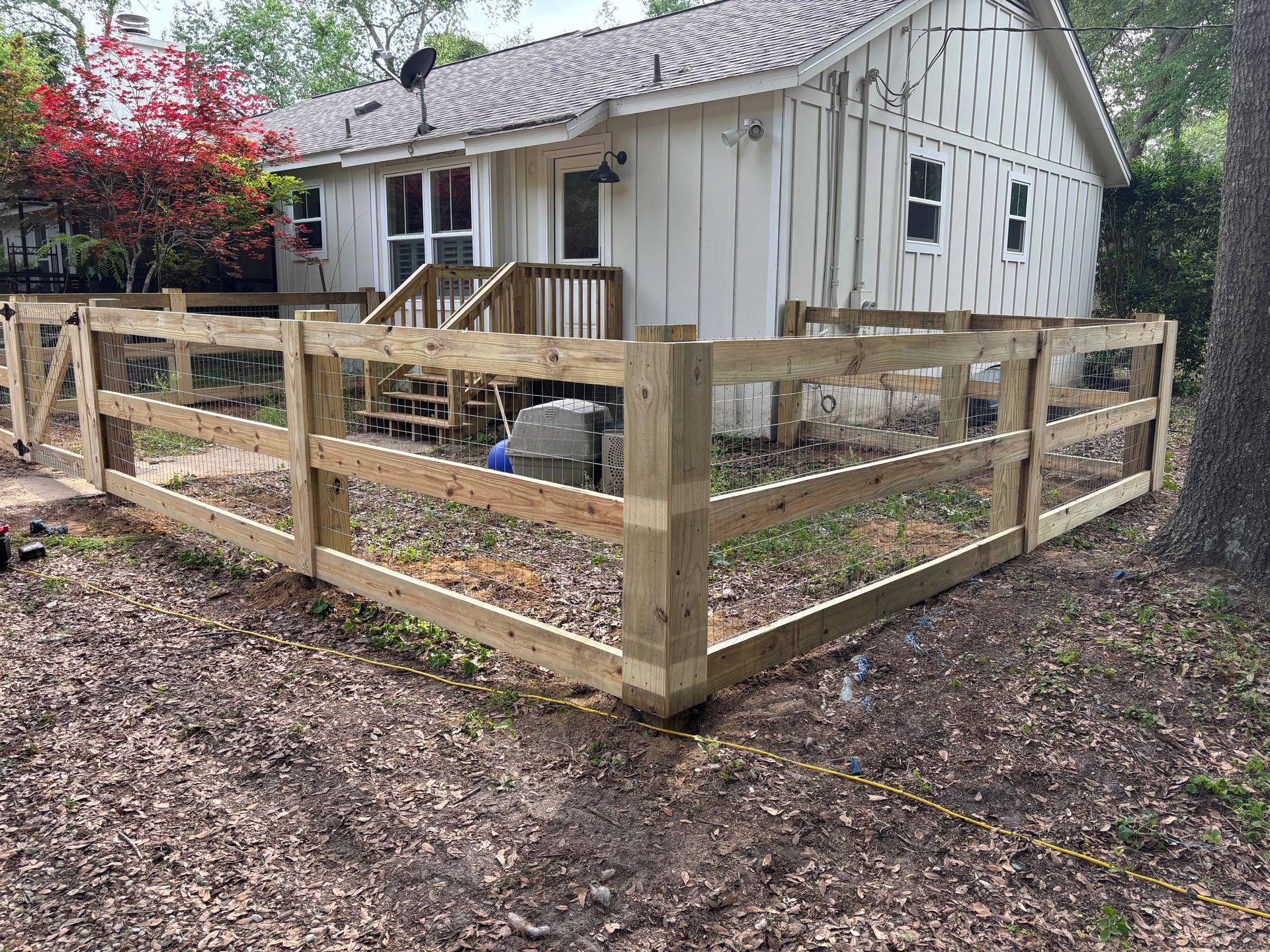 A wooden fence is in front of a white house.