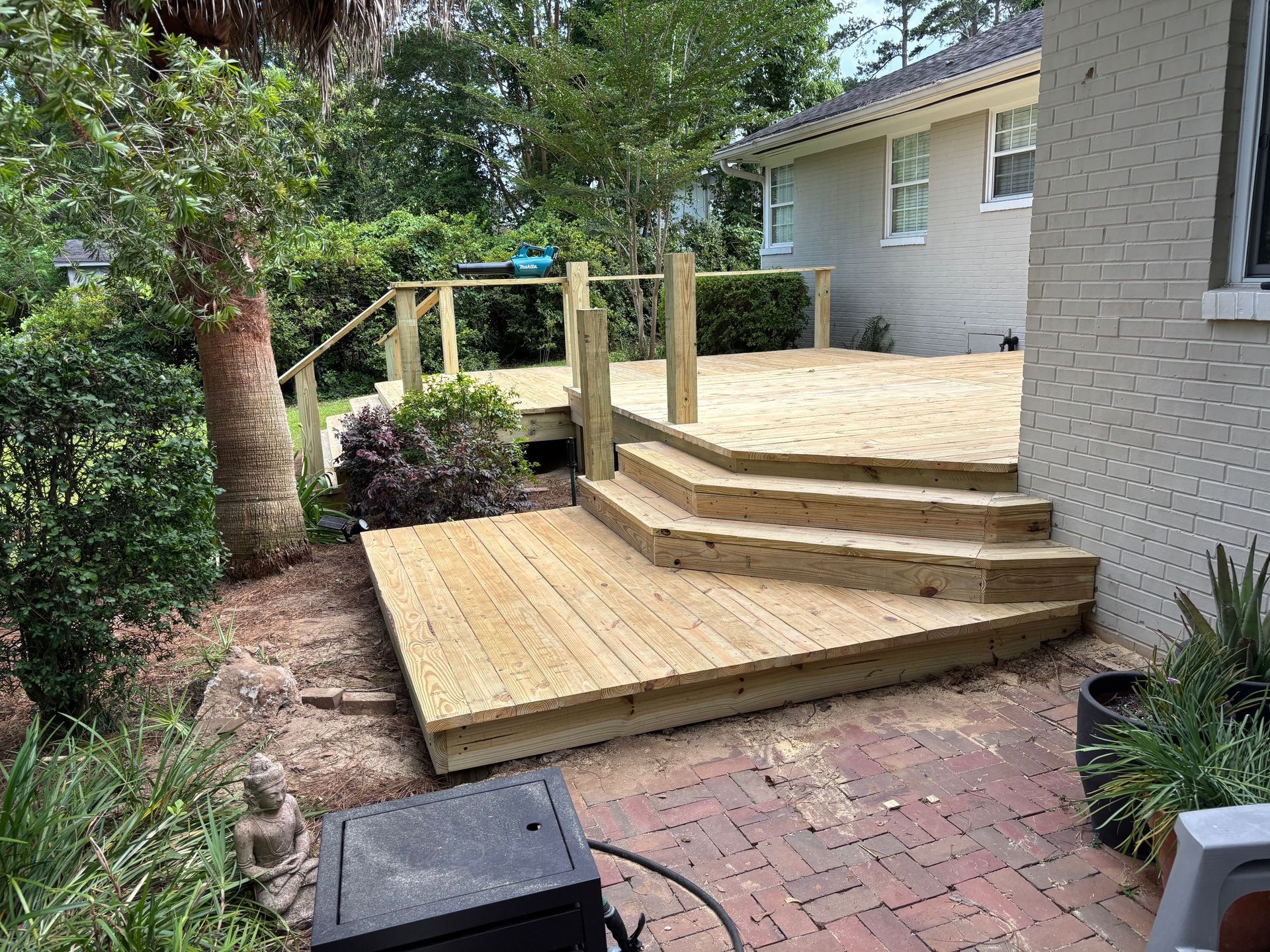A wooden deck with stairs leading up to it in front of a house.