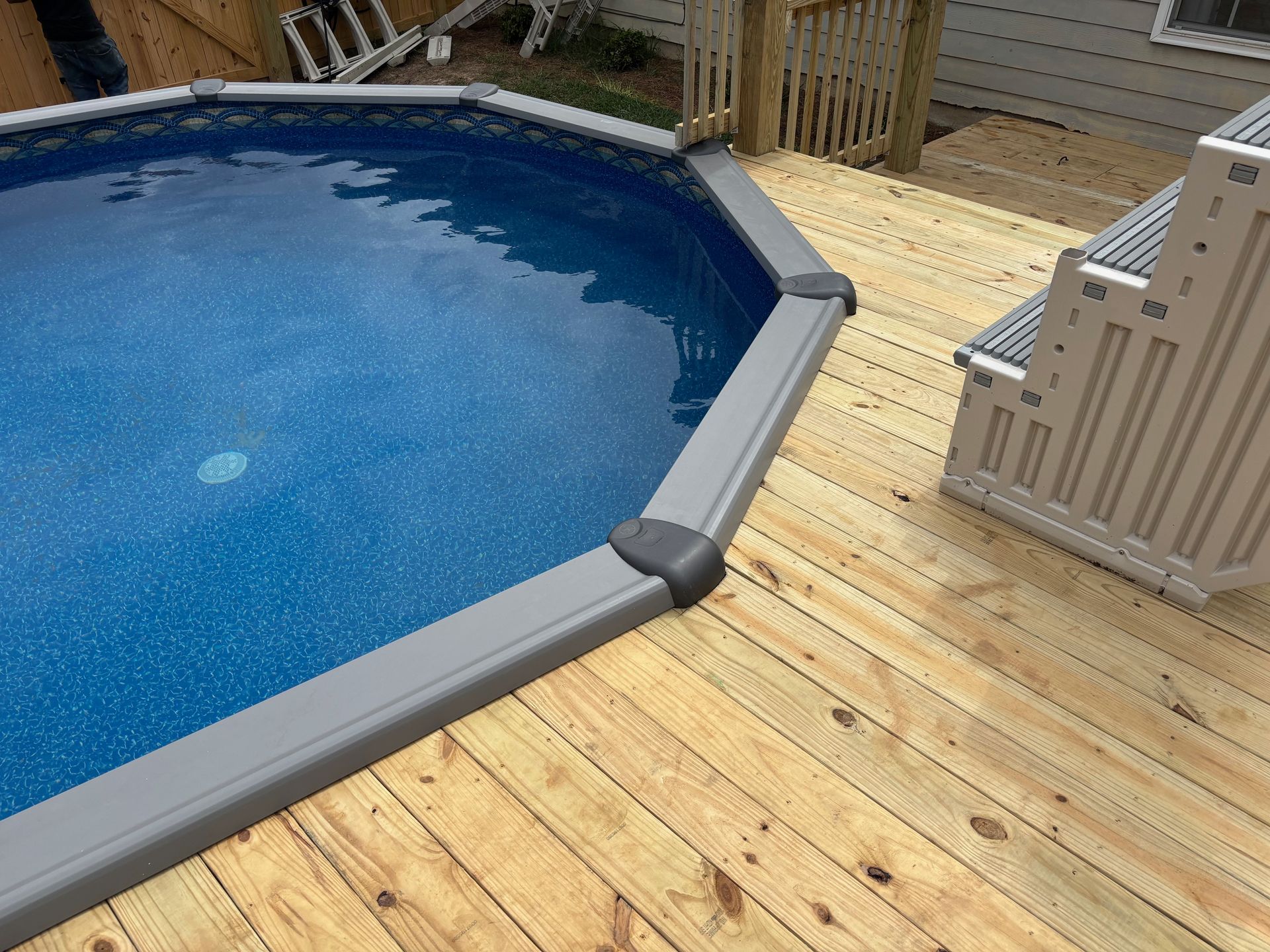 A swimming pool is sitting on top of a wooden deck.
