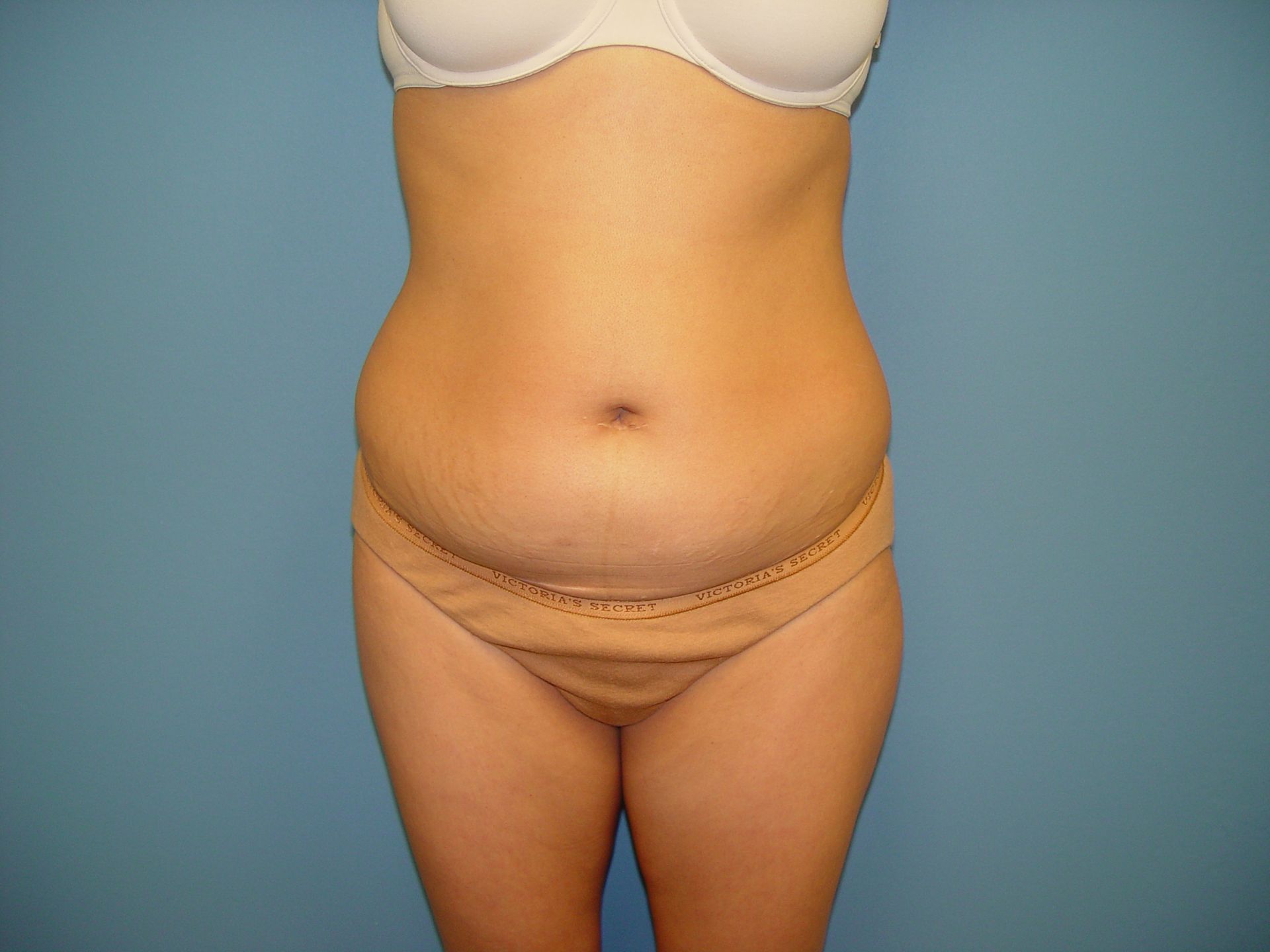 A woman in underwear is standing in front of a blue background.