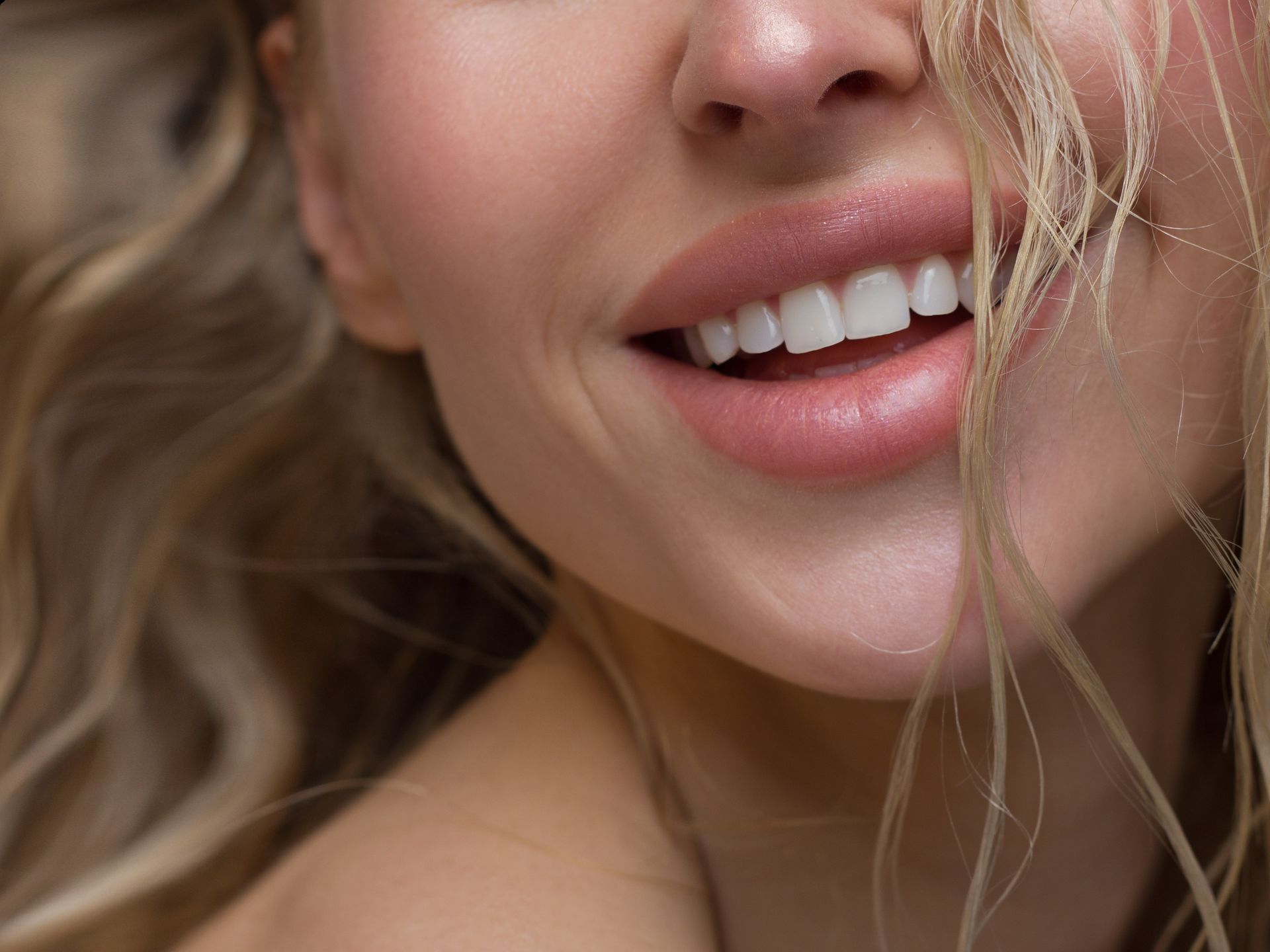 A close up of a woman 's face with her mouth open and her hair blowing in the wind.