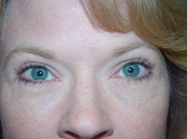 A close up of a woman 's face with blue eyes and blonde hair.