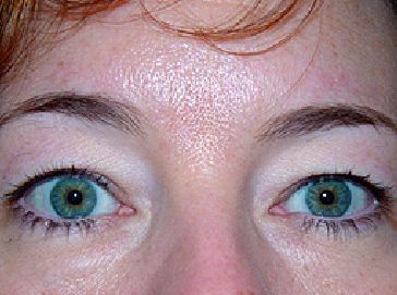 A close up of a woman 's face with green eyes.