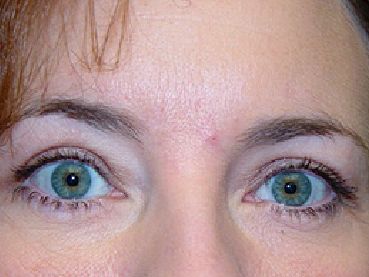 A close up of a woman 's face with green eyes.