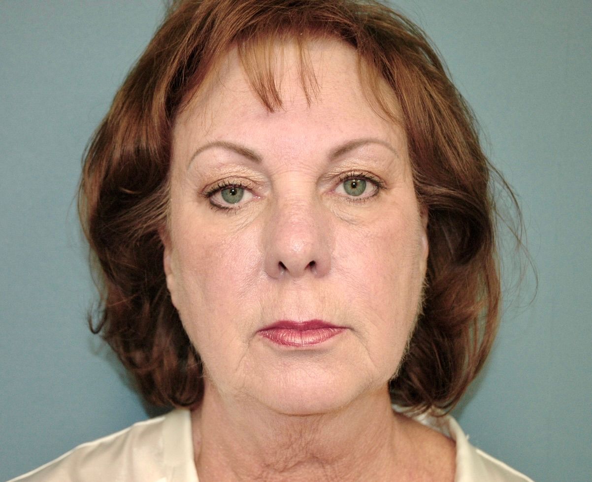 A woman with brown hair and green eyes is looking at the camera.