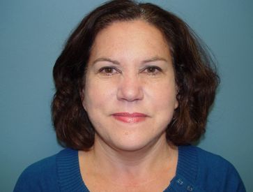 A woman in a blue sweater is smiling for the camera.