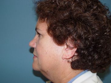 A woman with curly hair is standing in front of a blue wall.