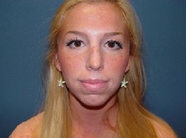 A woman with long blonde hair and earrings is looking at the camera.