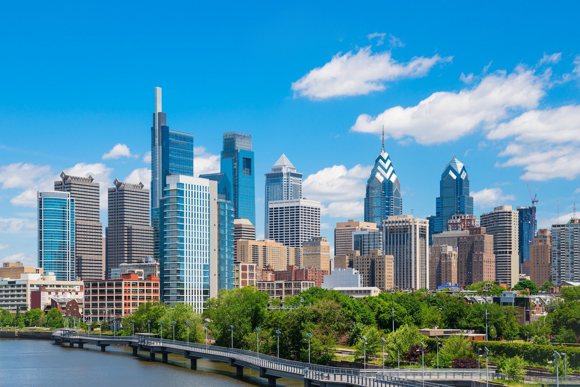 A city skyline with a river in the foreground and a bridge in the background.