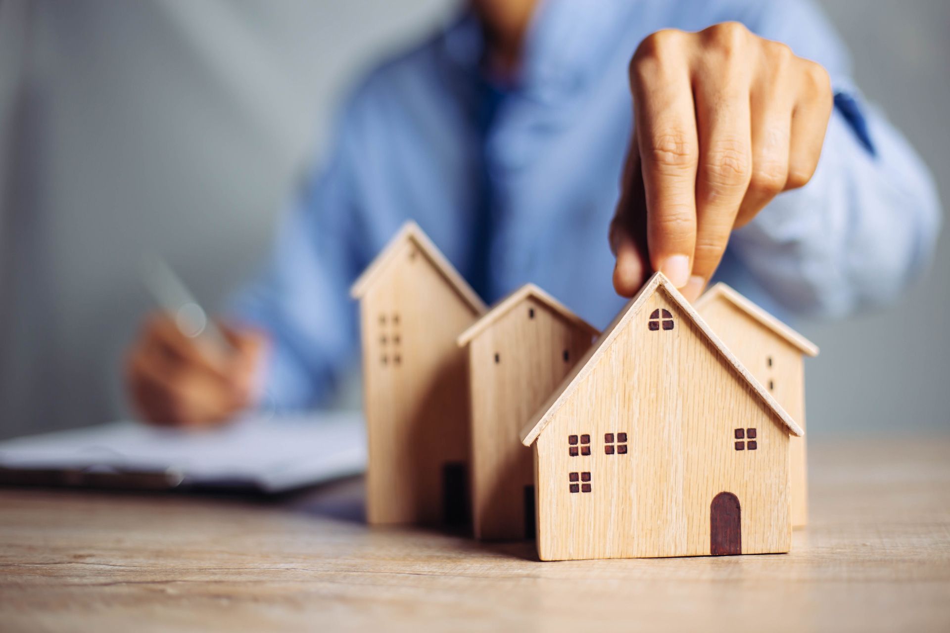 A person is putting a wooden house on top of a wooden table.