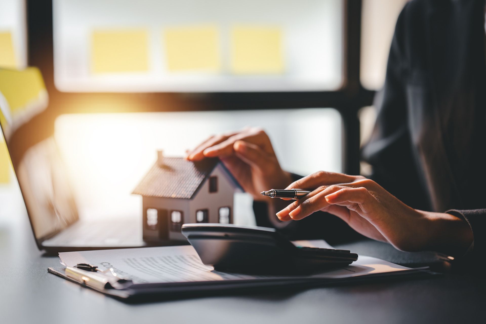 A person is using a calculator in front of a laptop computer.