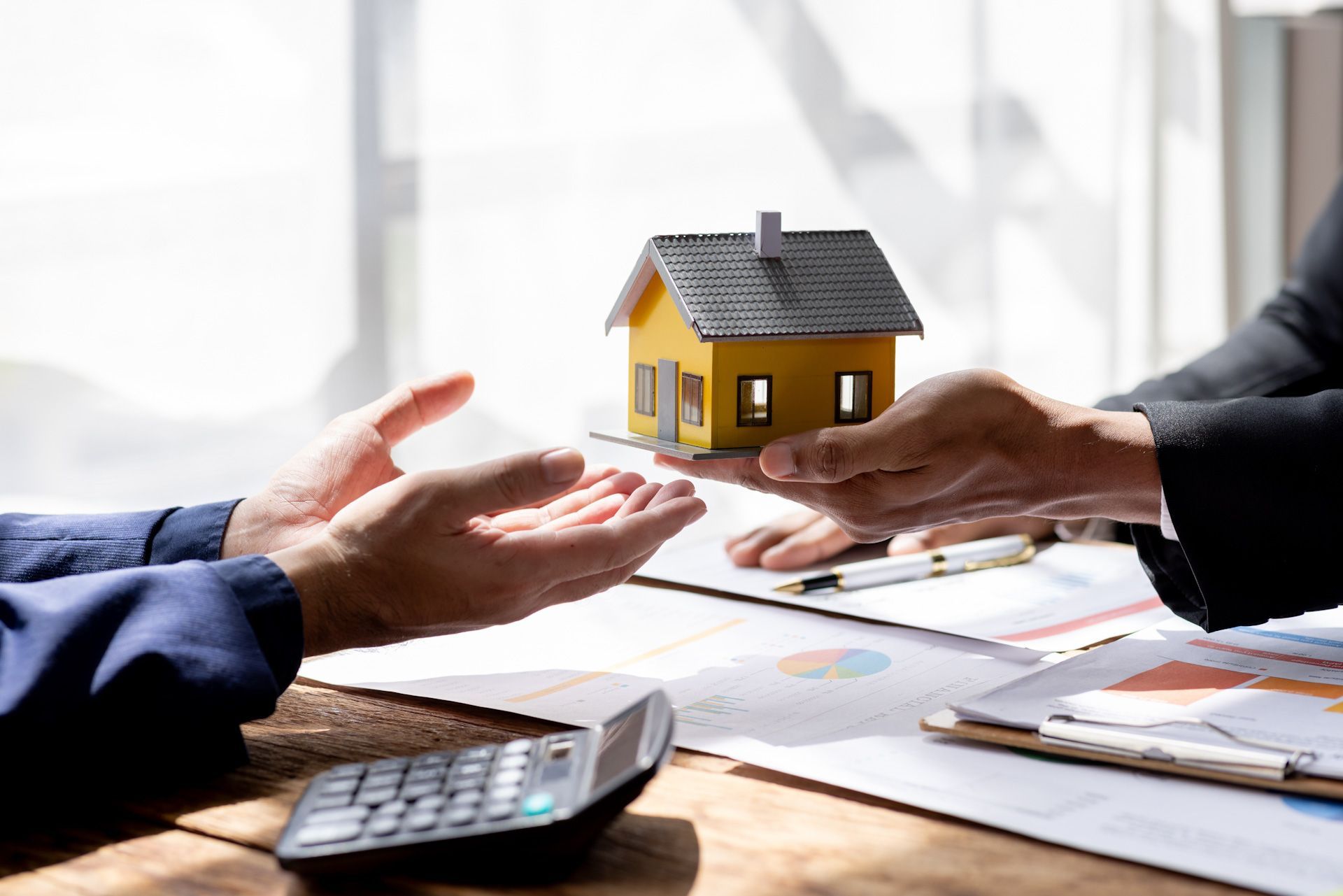 A man is handing a model house to another man.