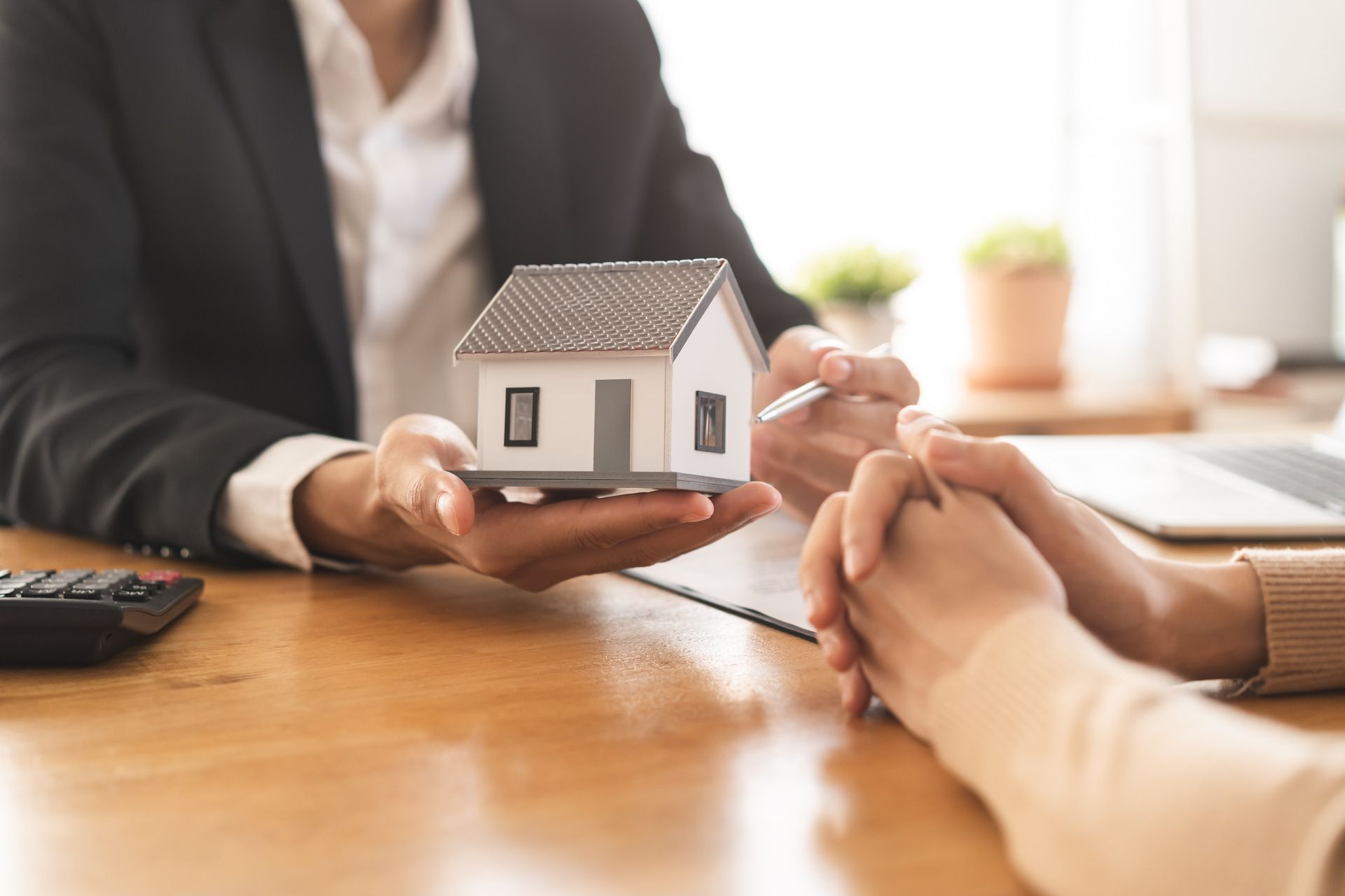 A man is holding a model house in front of a woman.