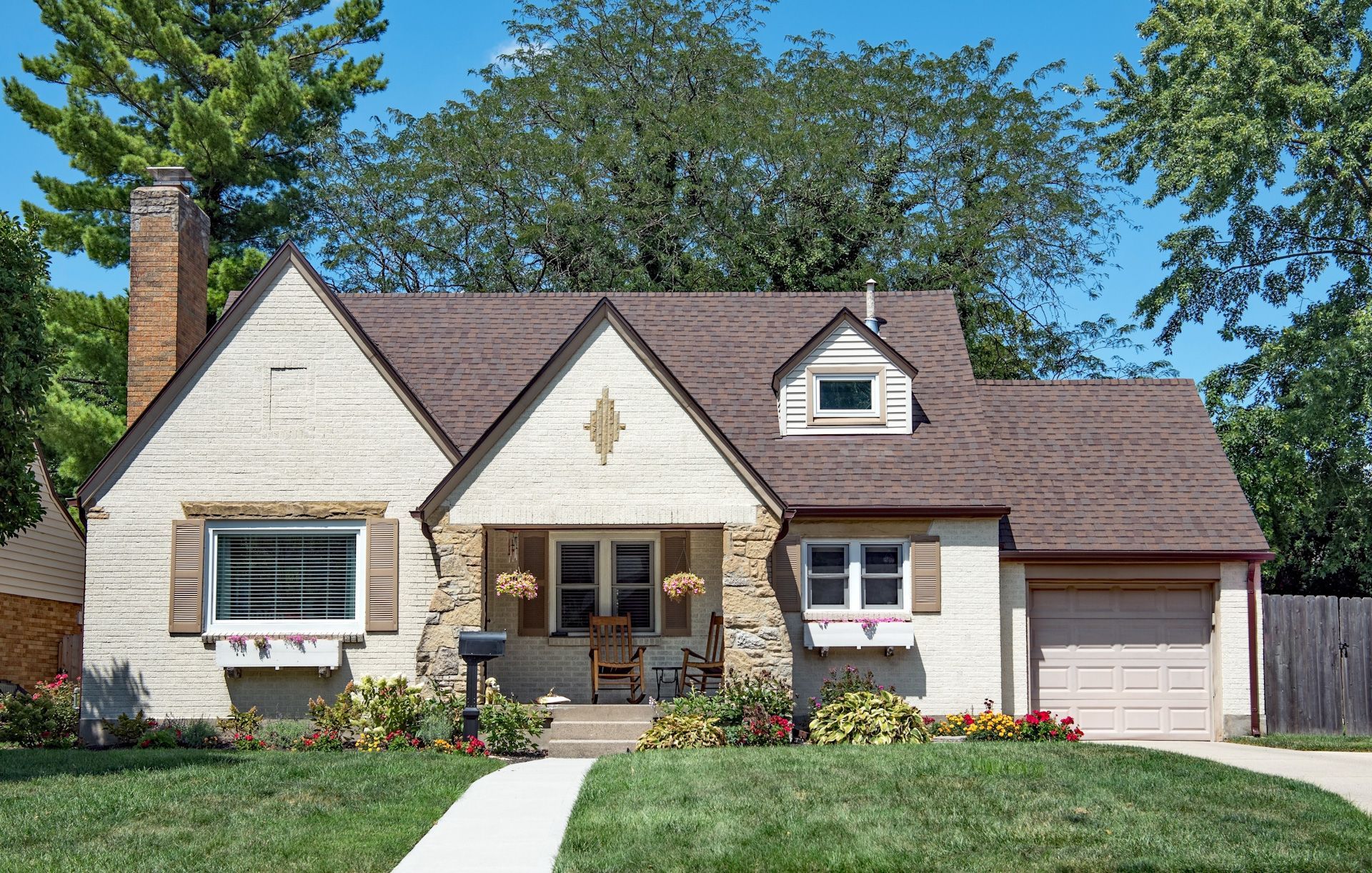 A white house with a brown roof and a porch
