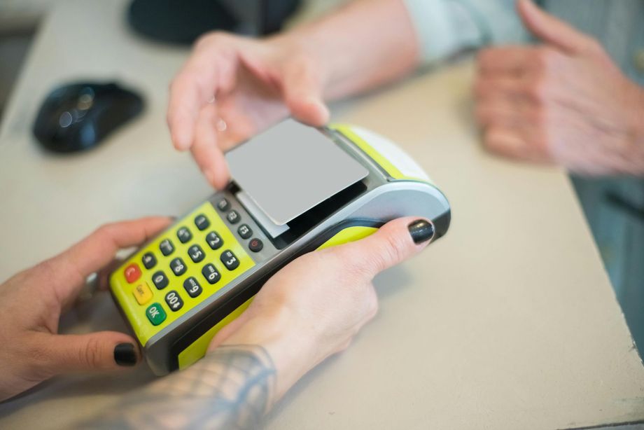 A person holding a payment terminal as a customer prepares to insert or tap a payment card.