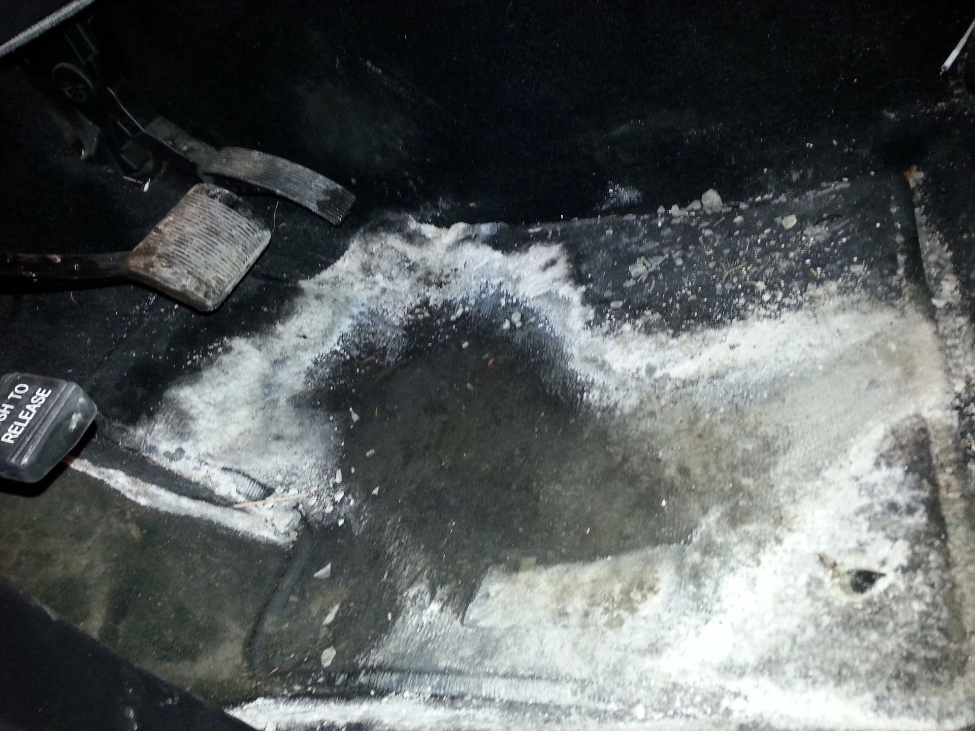 Interior car footwell with white salt residue. Black floor with pedals visible, dirty and discolored | Highlift Auto Service