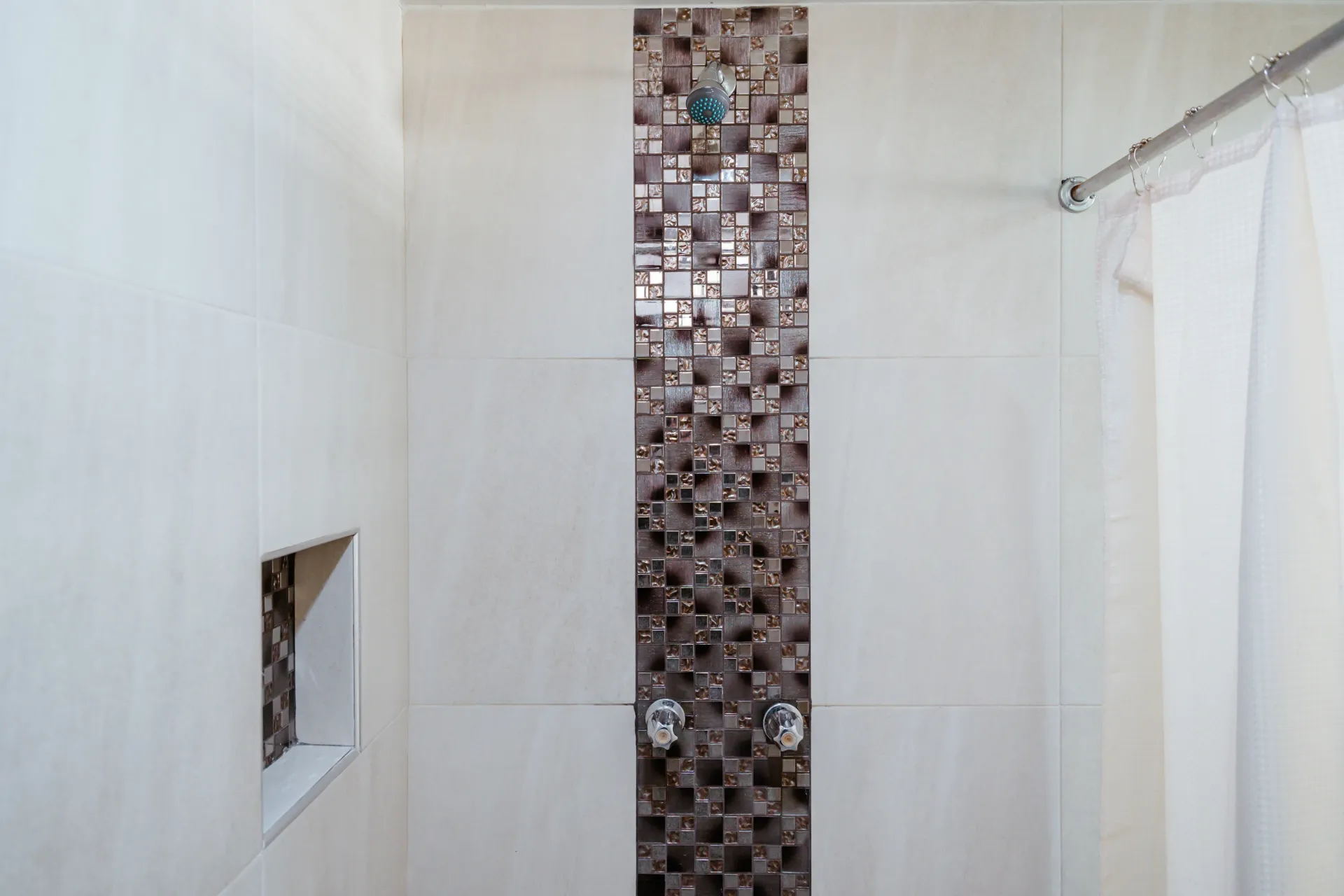 A bathroom with a shower and a tiled wall.