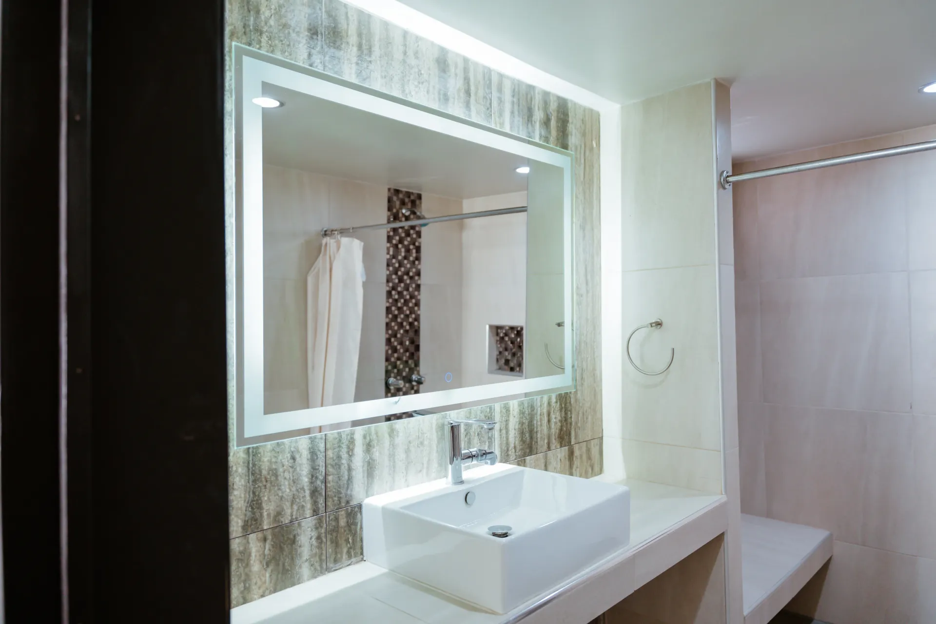 A bathroom with a sink , mirror and shower.