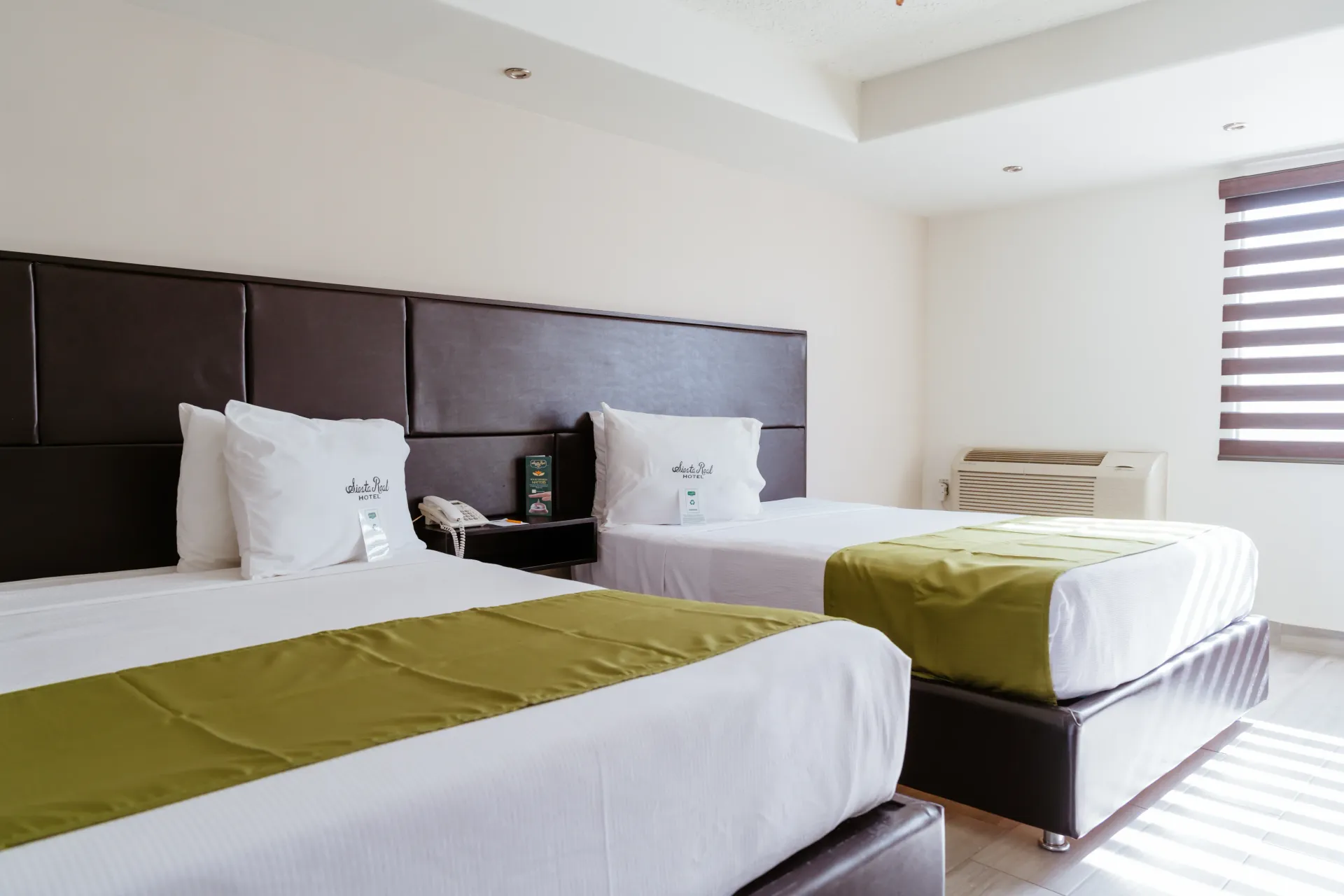 A hotel room with two beds and a window.