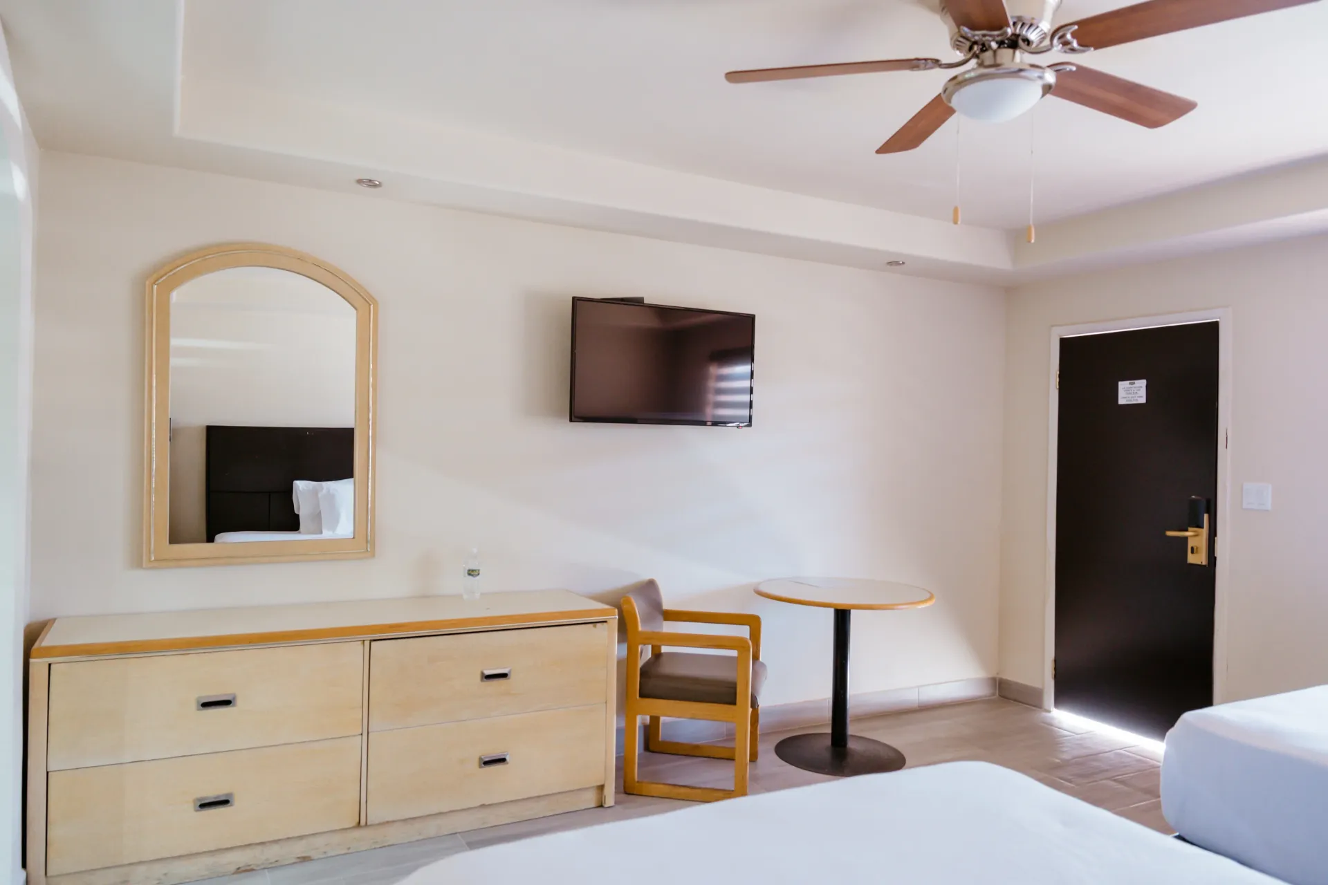 Una habitación de hotel con una cama, una cómoda, una silla, una mesa y una televisión.