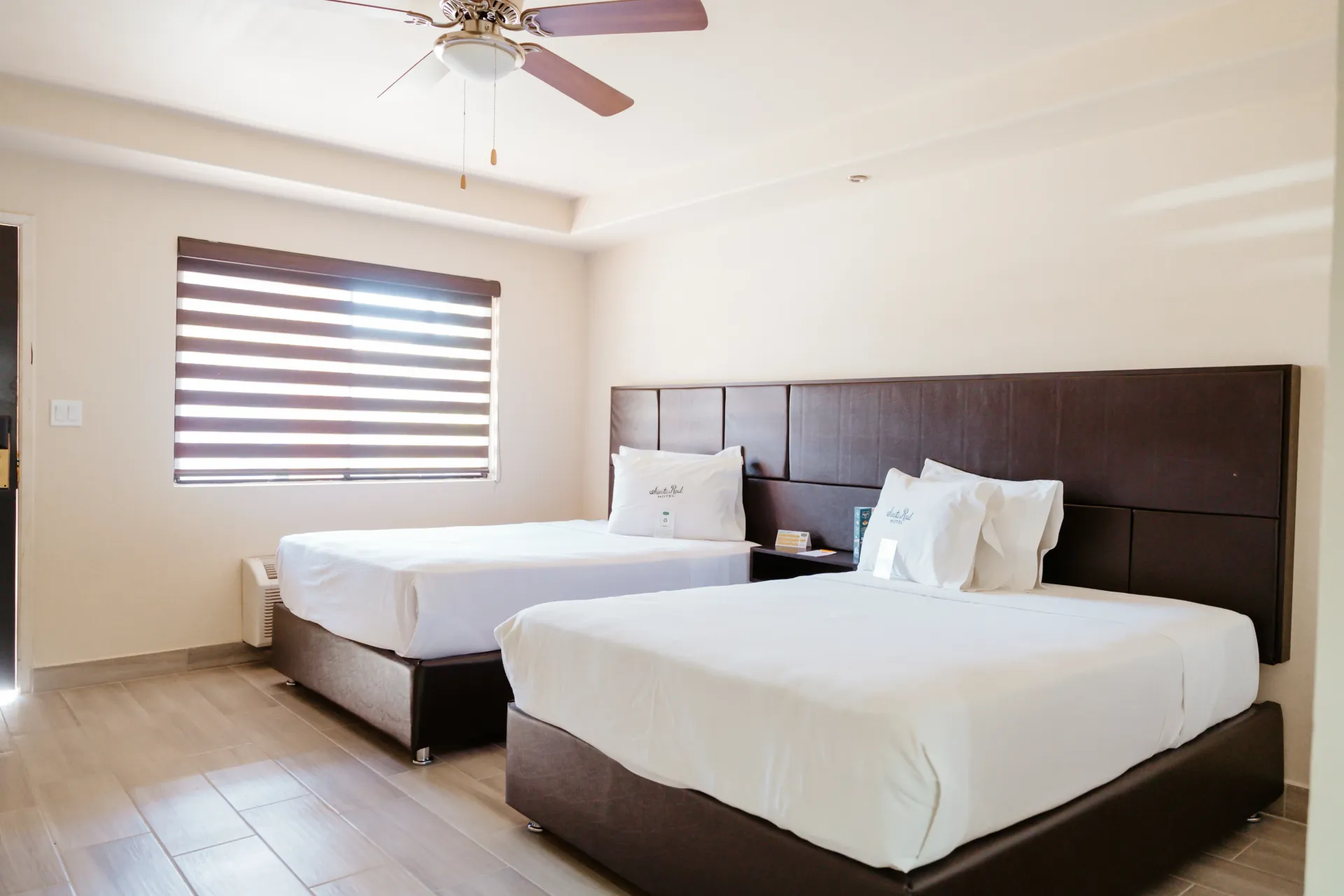 A hotel room with two beds and a ceiling fan.