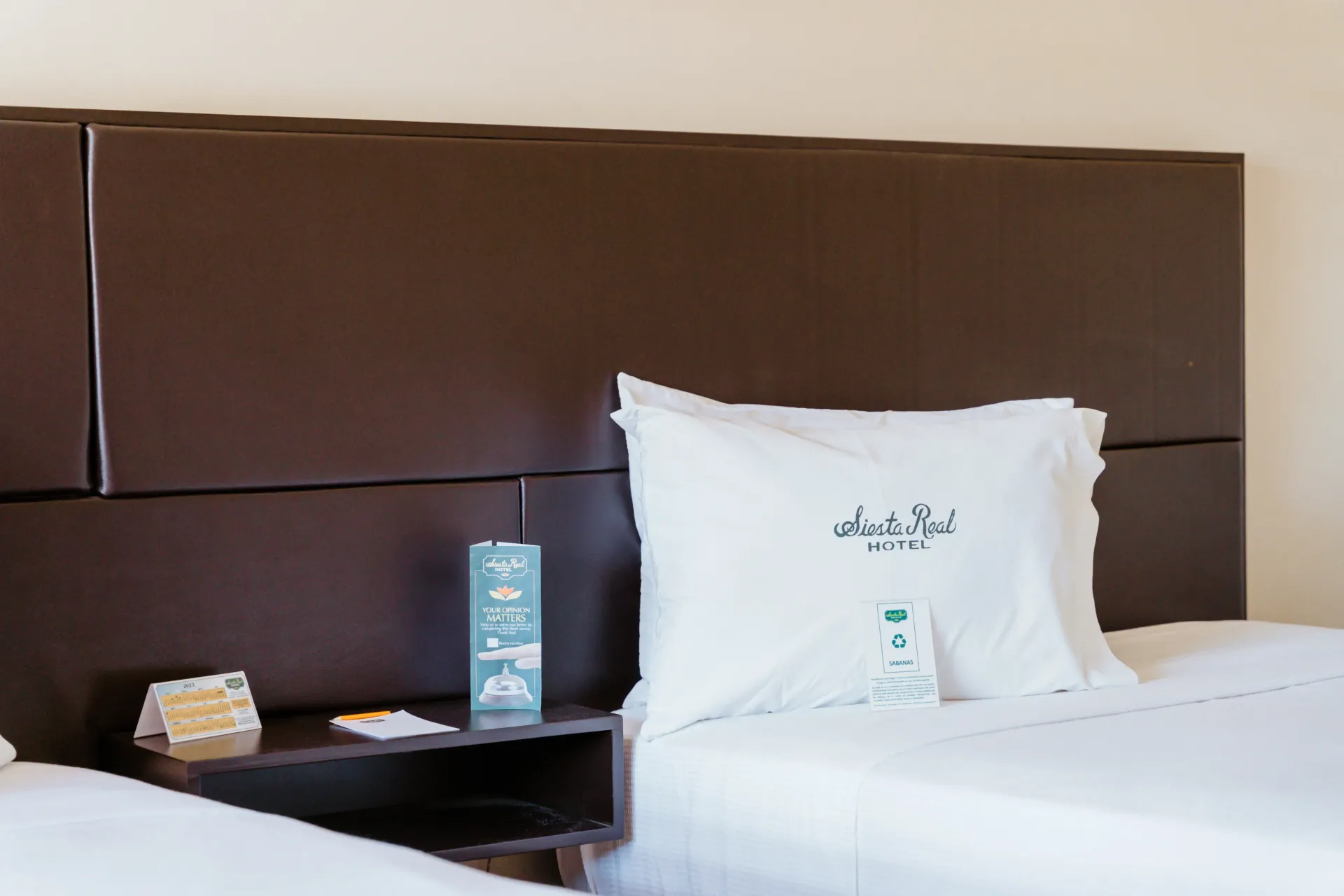 Una habitación de hotel con dos camas y un cartel en la mesita de noche.