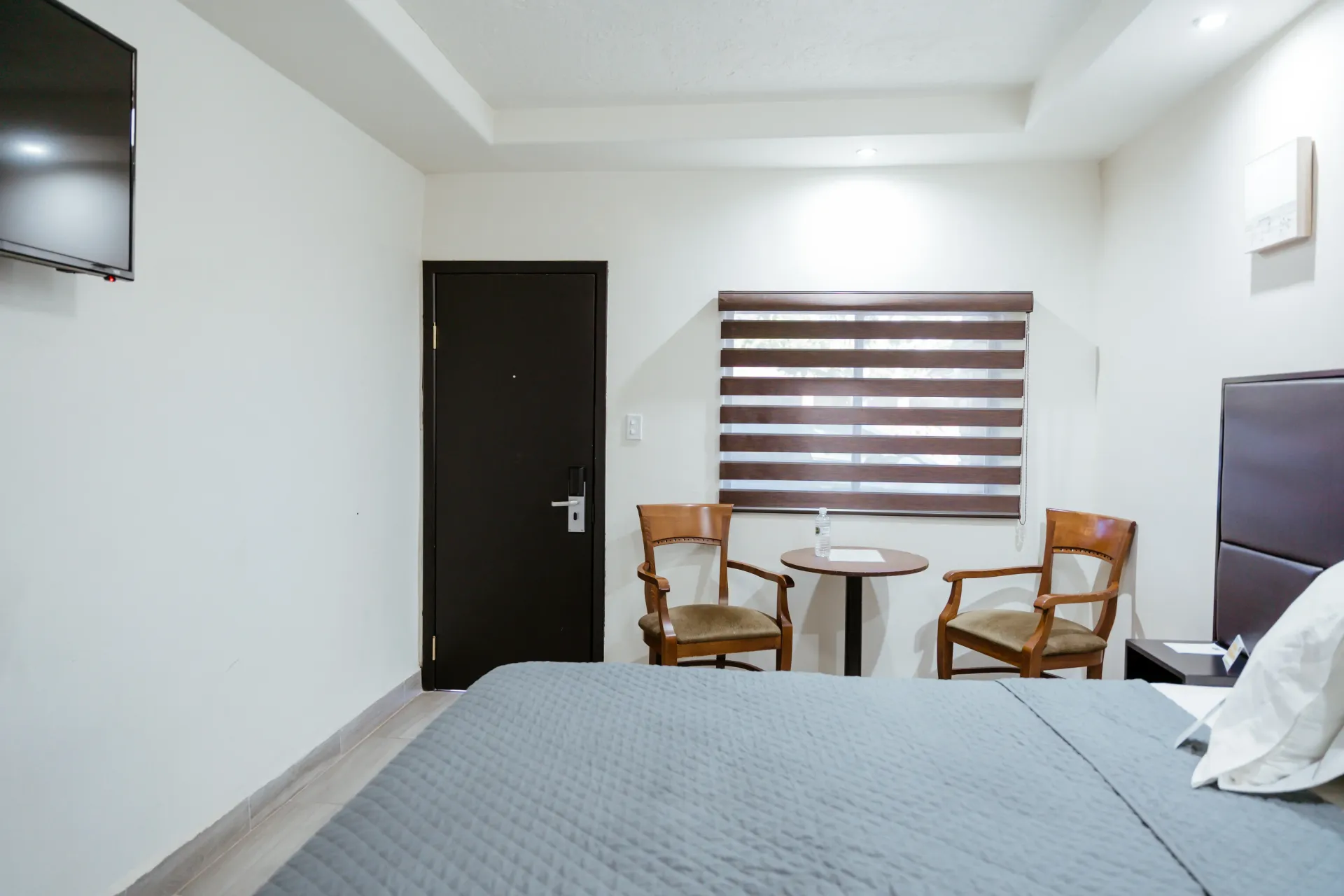 Una habitación de hotel con una cama grande y dos sillas.