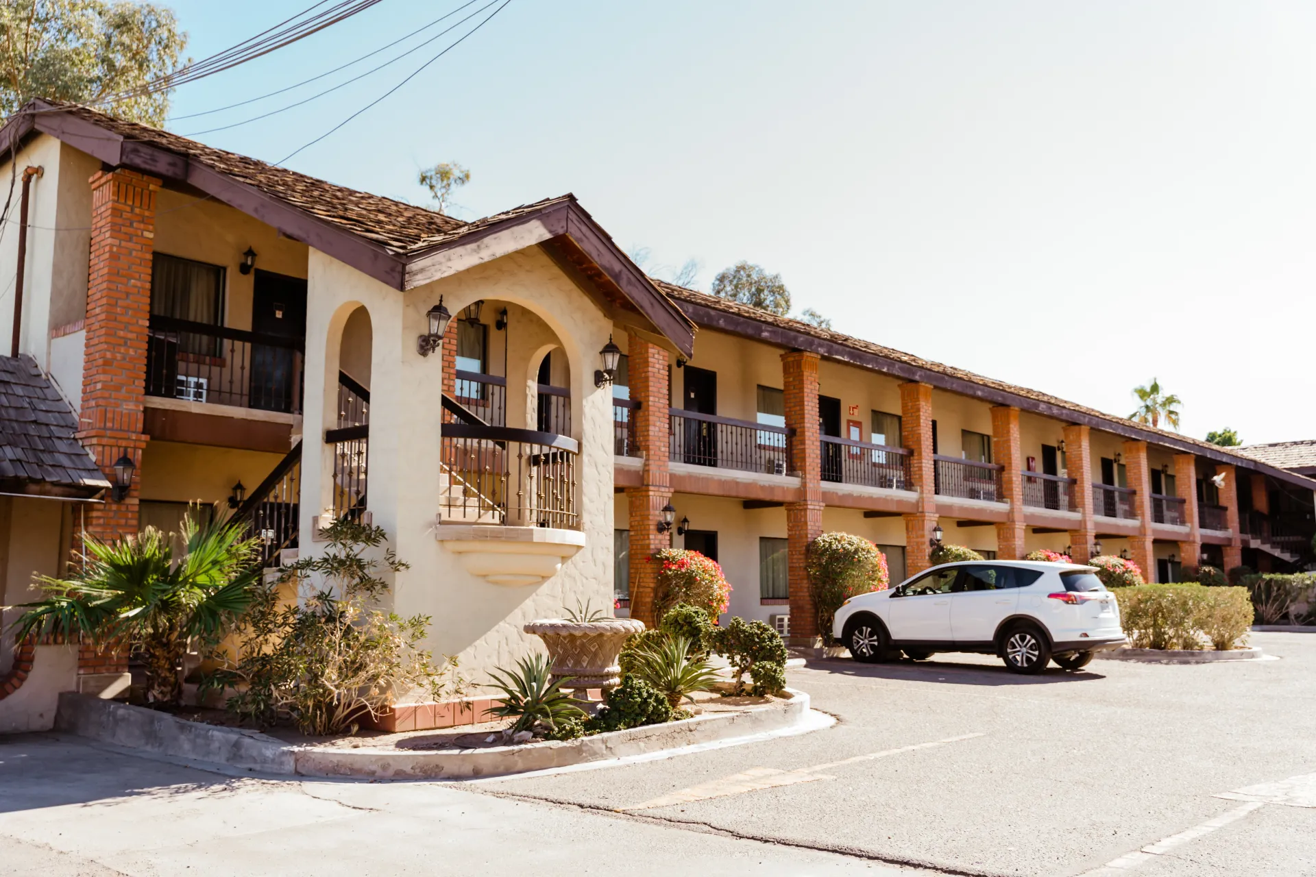 A white suv is parked in front of a hotel.