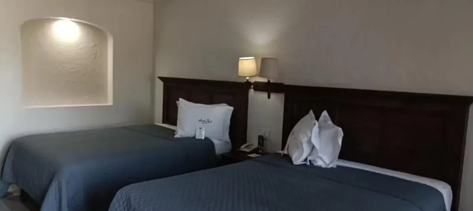 A hotel room with two beds and a lamp.