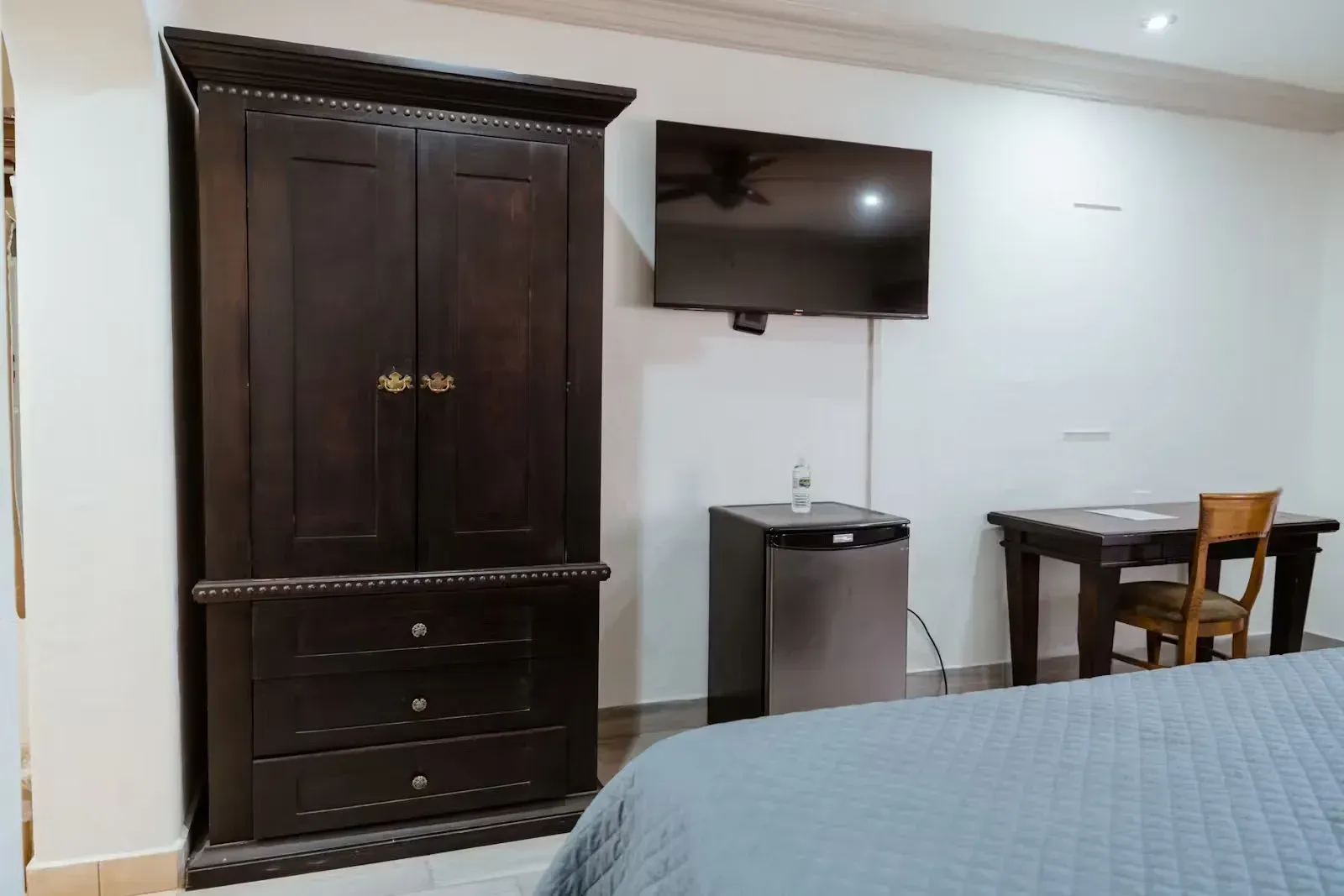 A hotel room with a bed , dresser , desk and television at Siesta Real Mexicana Hotel.