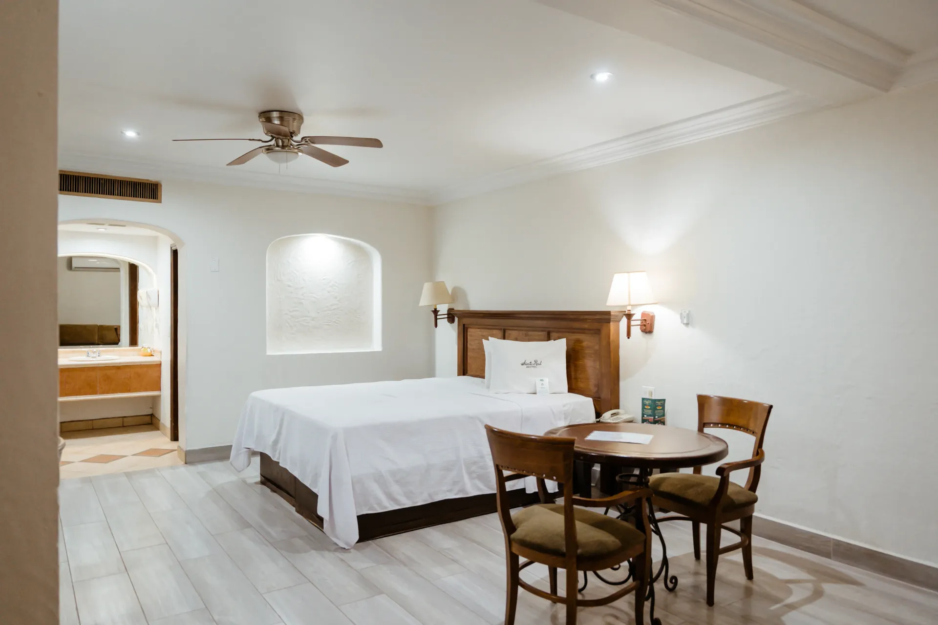 A hotel room with a king size bed , table and chairs.