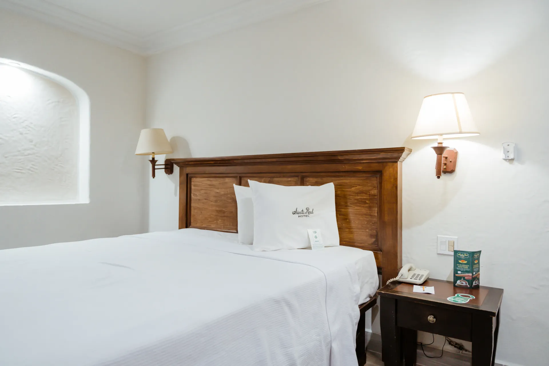 A hotel room with a king size bed and a nightstand.